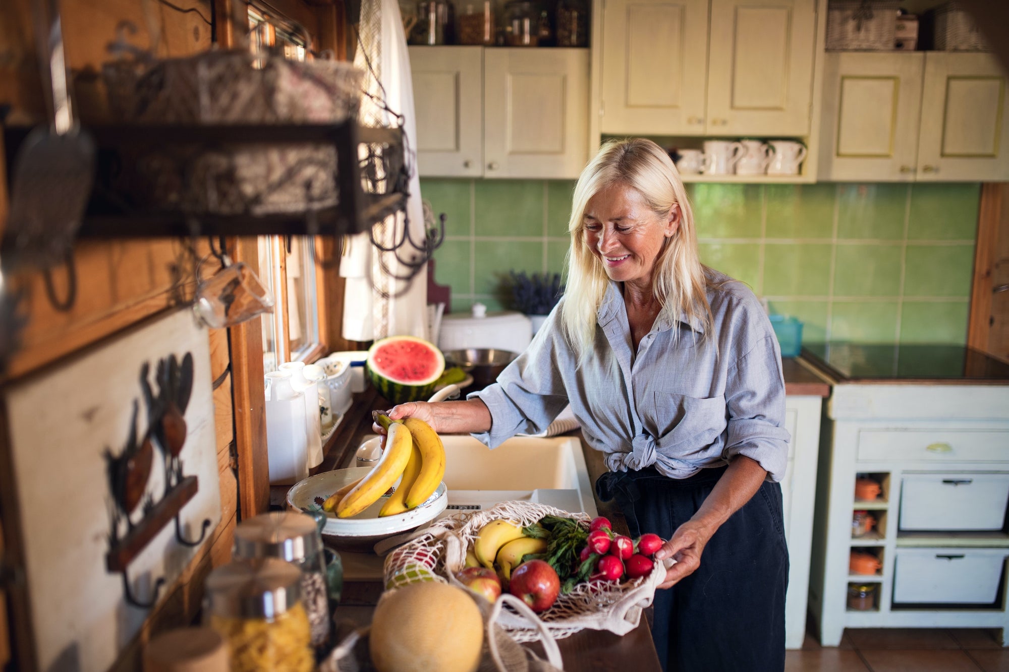eco friendly, green kitchen with reusable shopping bags, woman and fruit